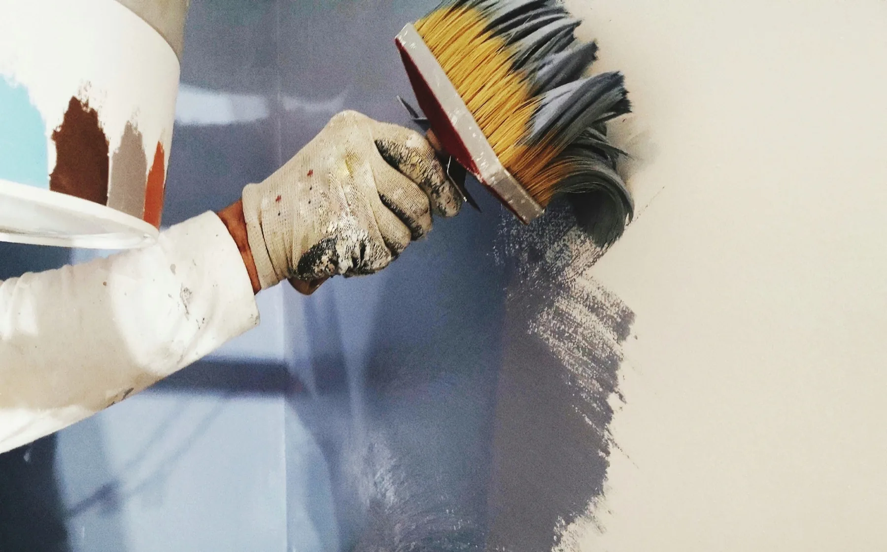 A painter brushing color onto a wall
